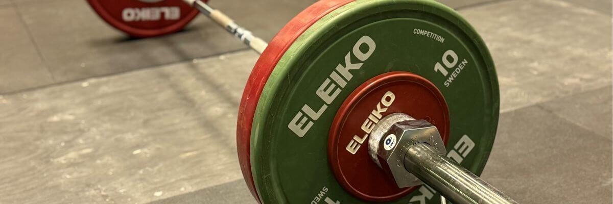 Eleiko vægtstang med røde og grønne skiver.